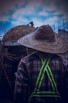A construction worker in reflective gear looks at a building dome under construction.