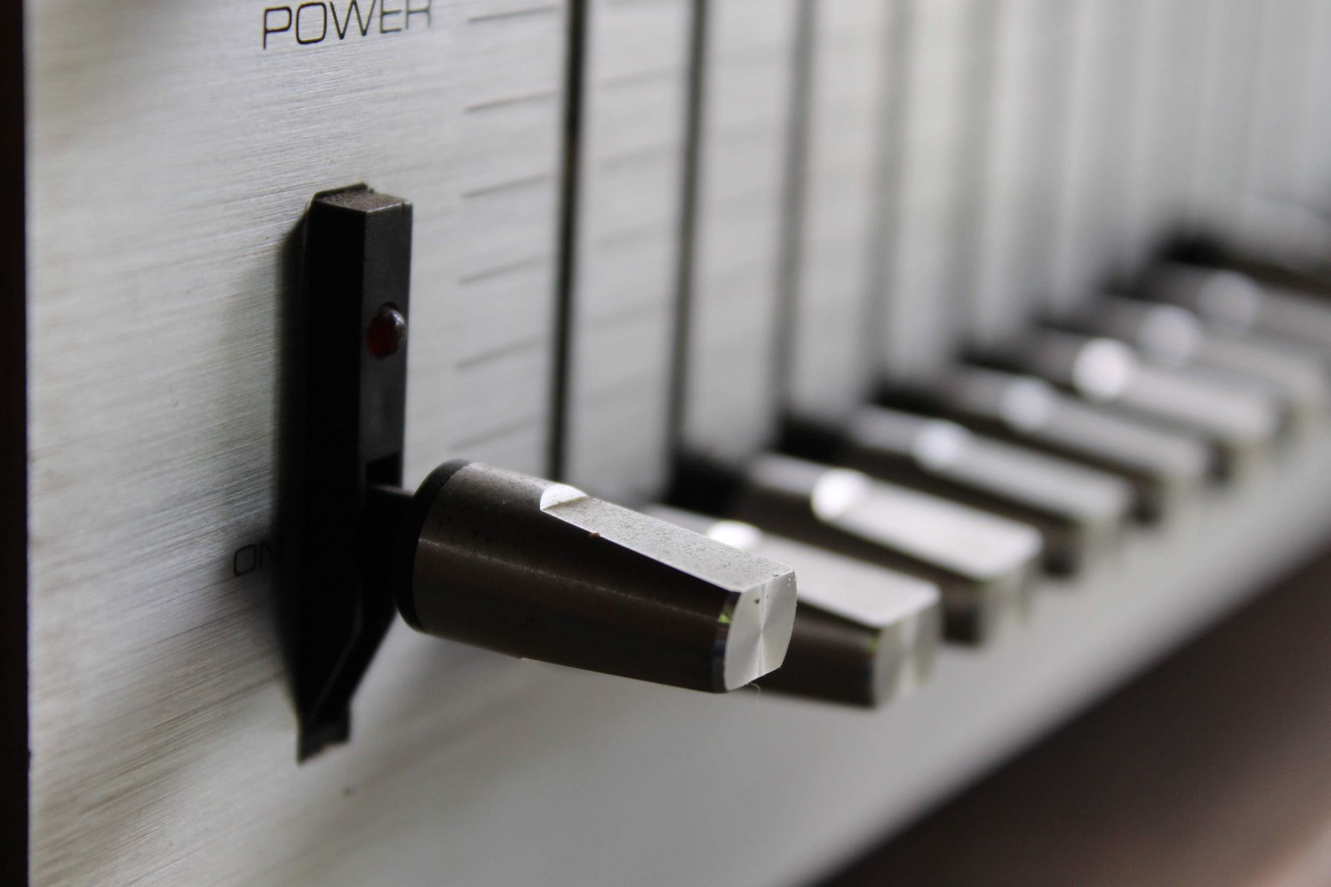 Detailed view of a vintage audio control panel switch and sliders in focus.