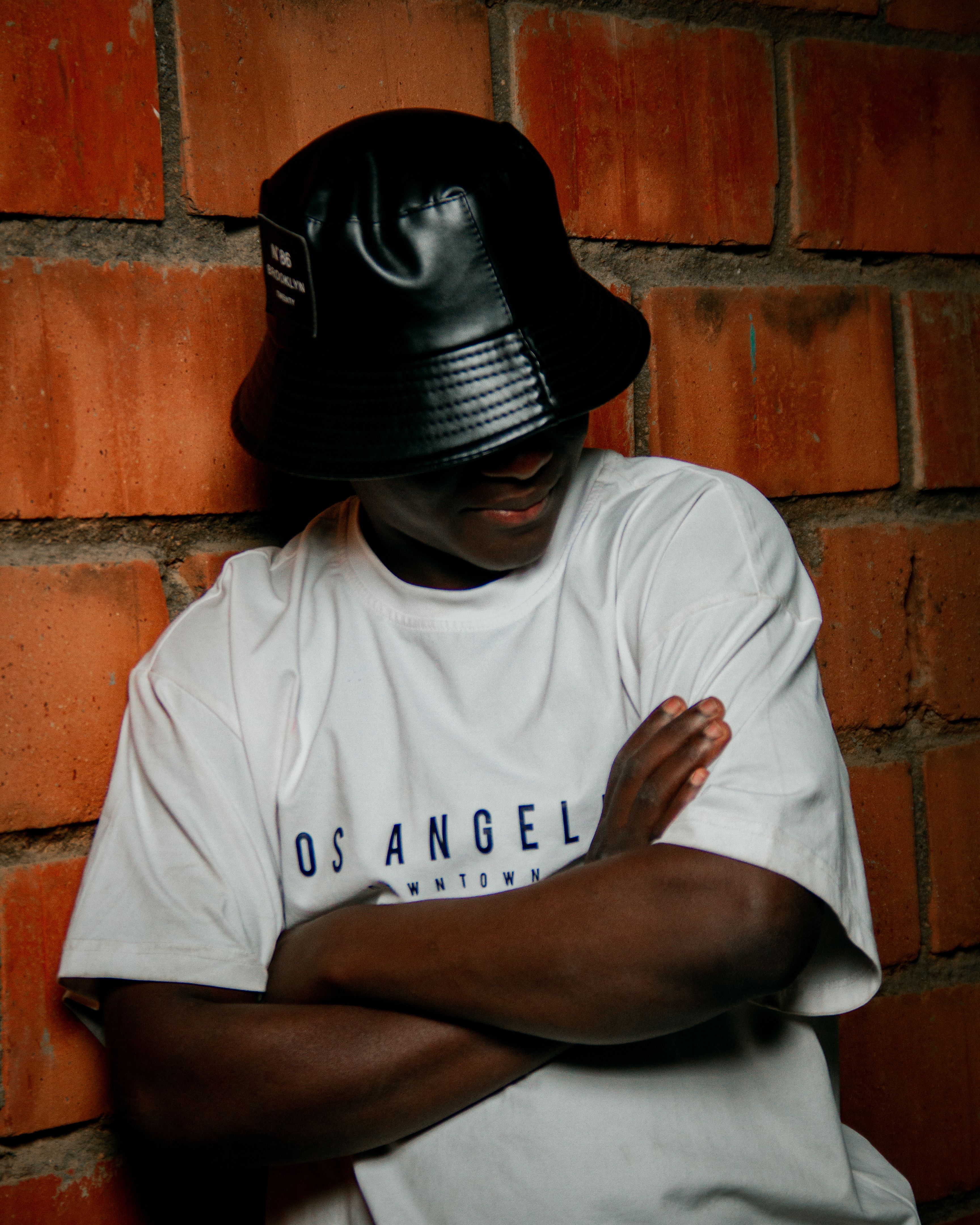 Stylish Man in Bucket Hat Against Brick Wall · Free Stock Photo