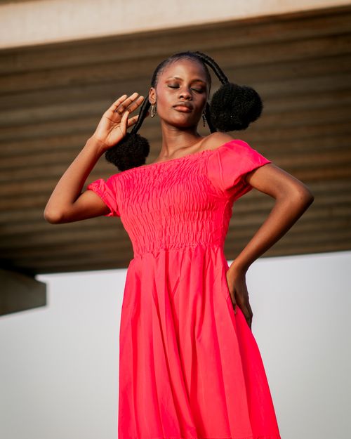 Free Graceful woman in a vivid red dress posing outdoors on a sunny day. Stock Photo