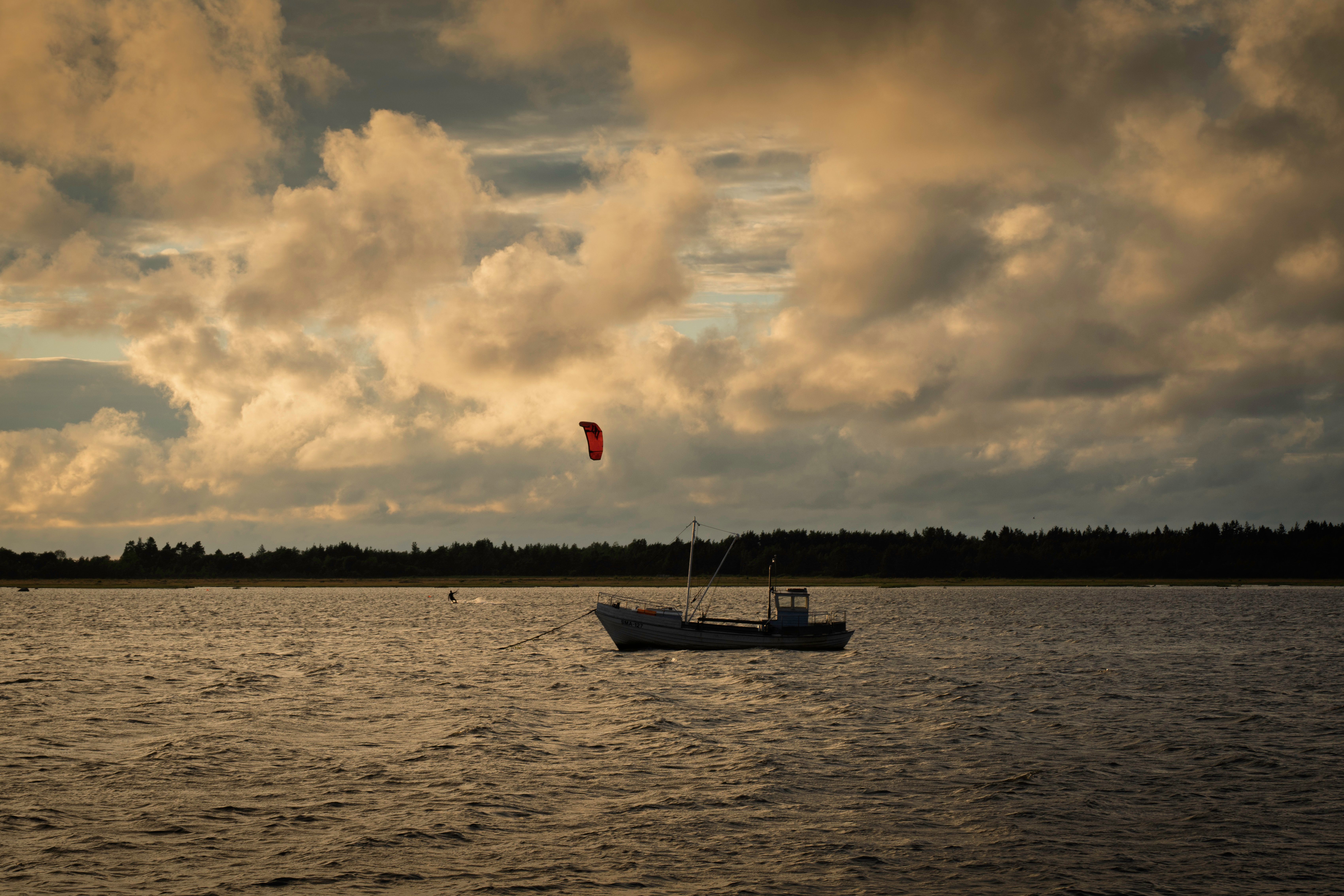 A tranquil scene of a lone boat and kite under dramatic evening clouds in Vilsandi, Estonia. — Trójmiasto