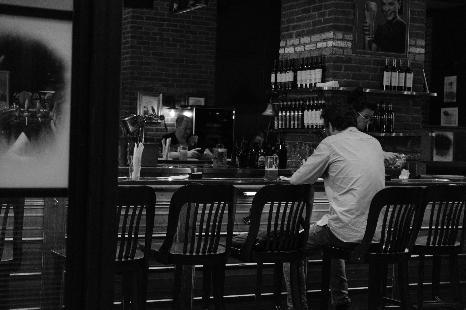 A classic black and white photo of a cozy Montreal bar with patrons enjoying a drink.