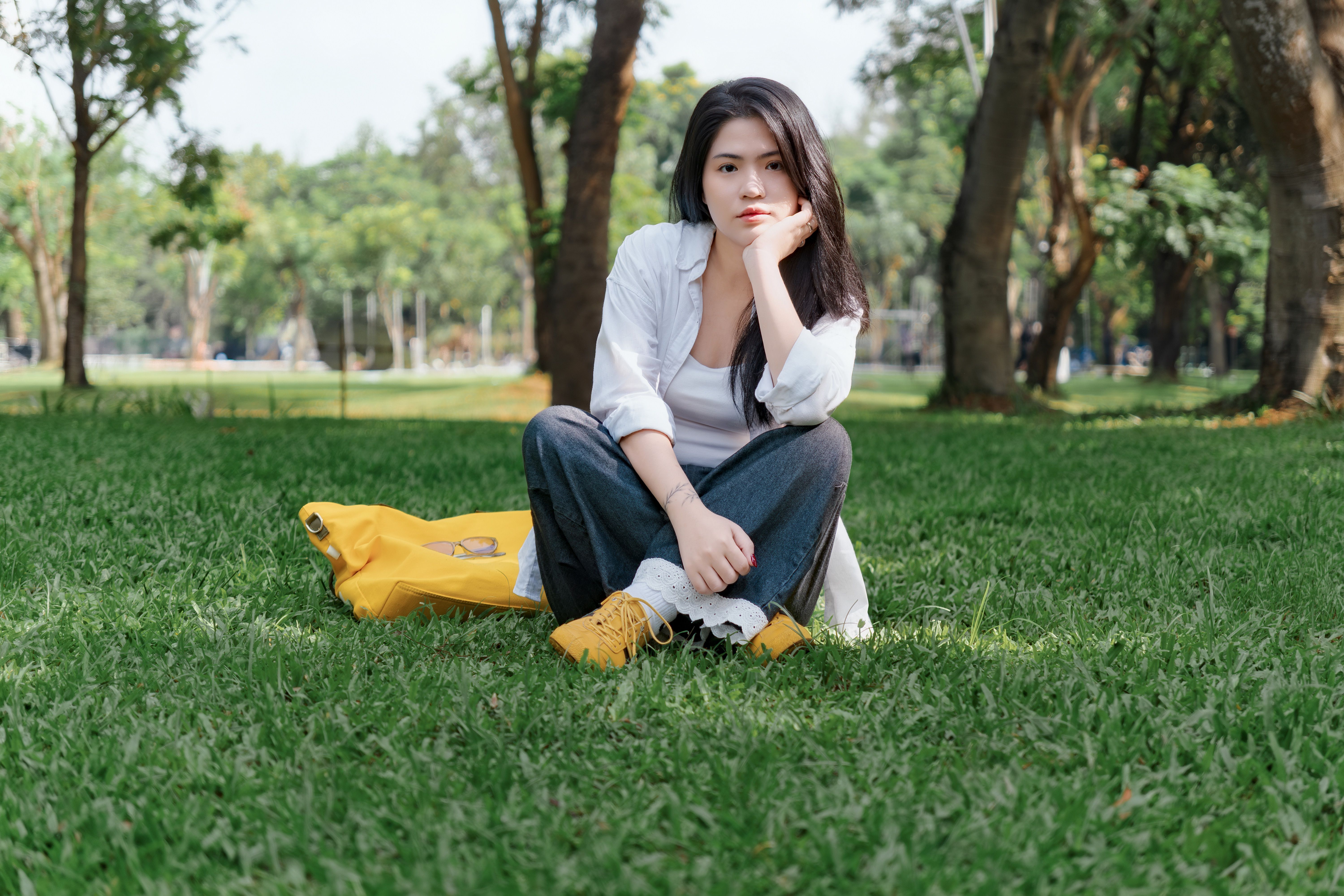 Jovem sentada na grama de um parque ensolarado, aproveitando o contato direto com a natureza para regulação emocional