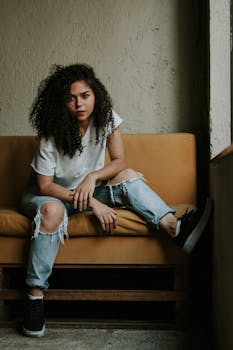 一位自信的女人，卷着头发，穿着休闲装，坐在室内的沙发上