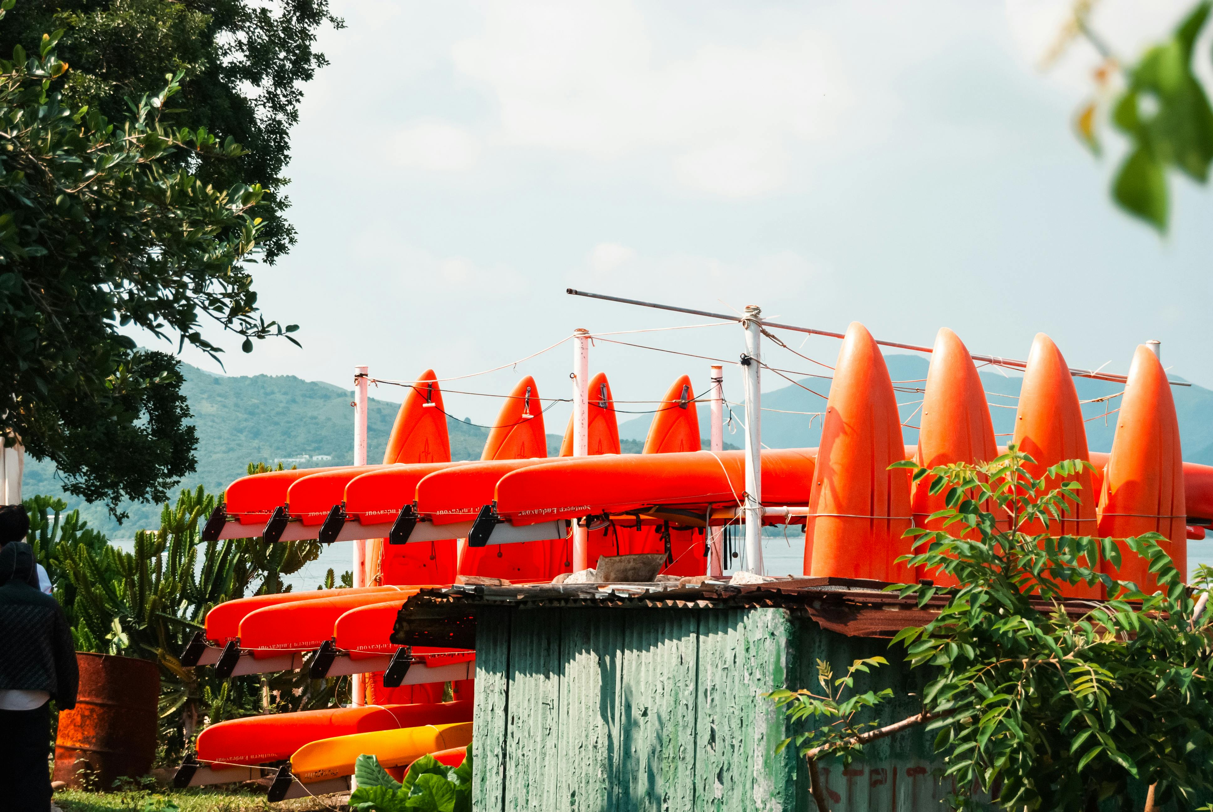 Vibrant red canoes stacked by a lakeside, ideal for summer adventures.