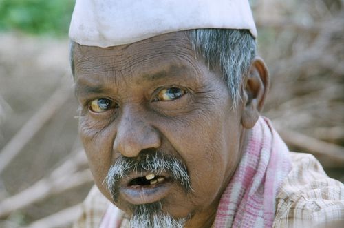 Free Portrait of an elderly man wearing a traditional cap outdoors in a rural environment. Stock Photo