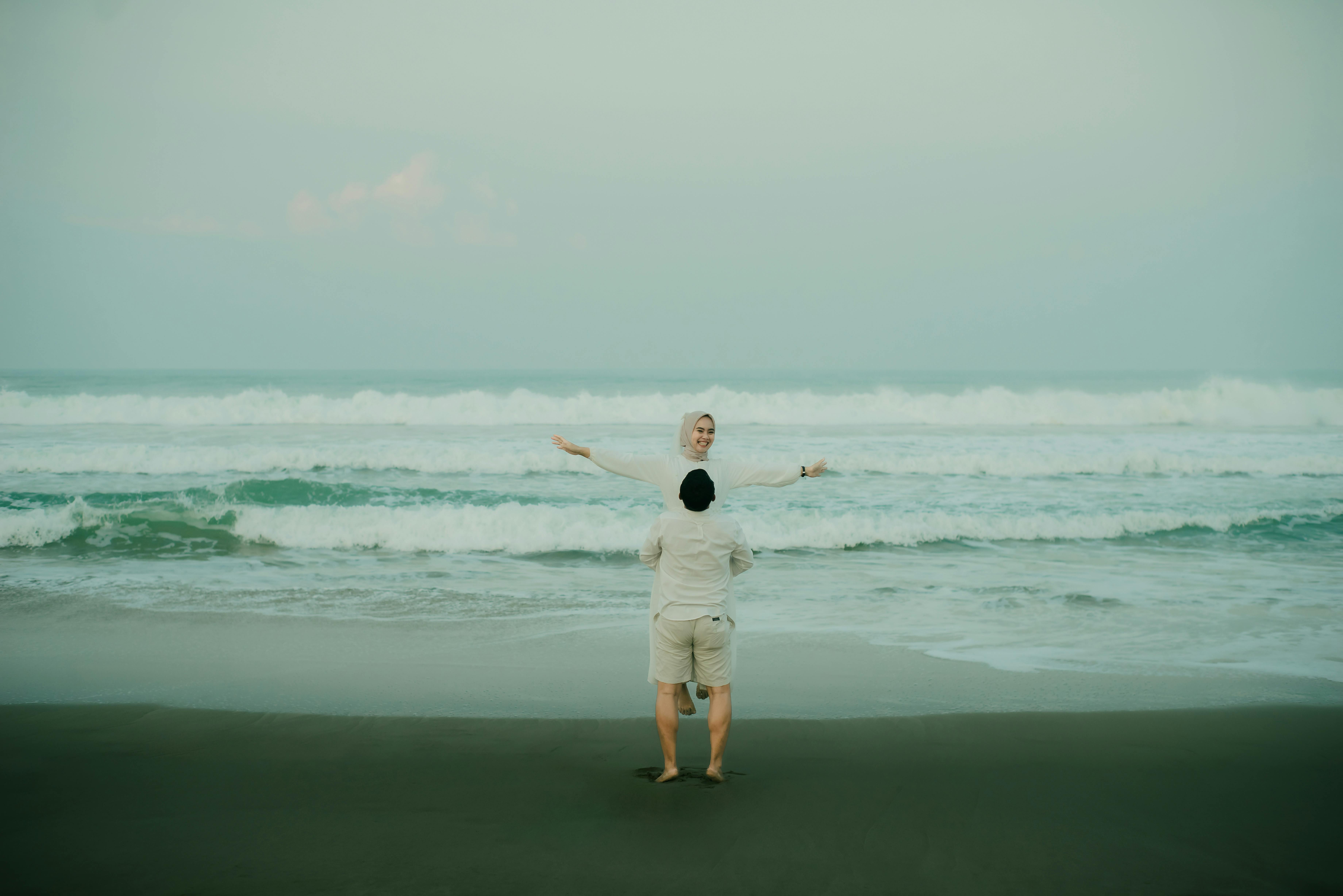 A couple shares a tender moment on a Banten beach, with serene waves in the background.