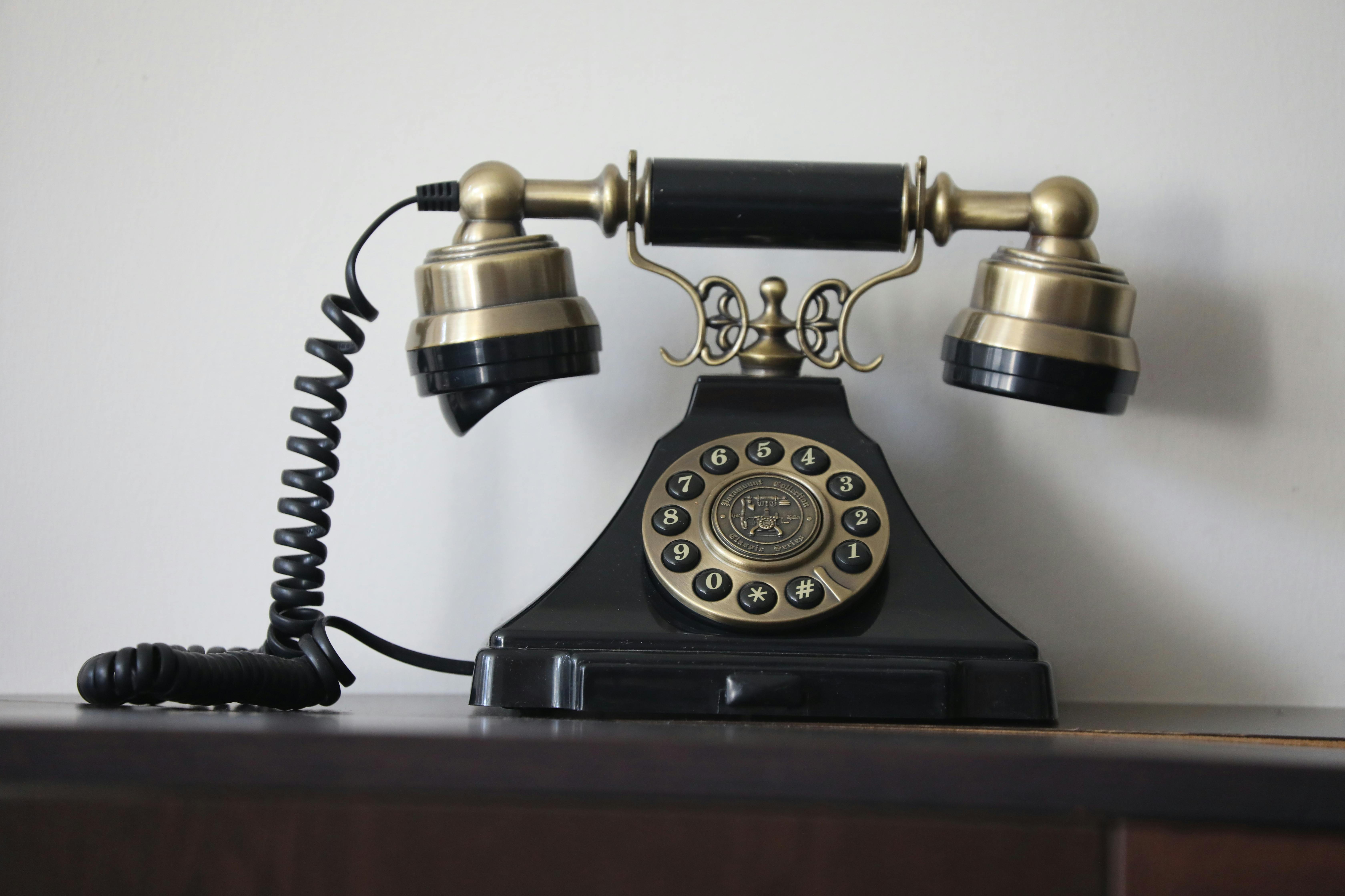 Kostenlos Klassisches Wählscheibentelefon in Schwarz und Messing mit antikem Design, das Nostalgie weckt. Stock-Foto