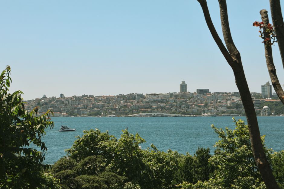Beautiful view of Istanbul cityscape across the Bosphorus Strait with lush greenery and a passing boat.