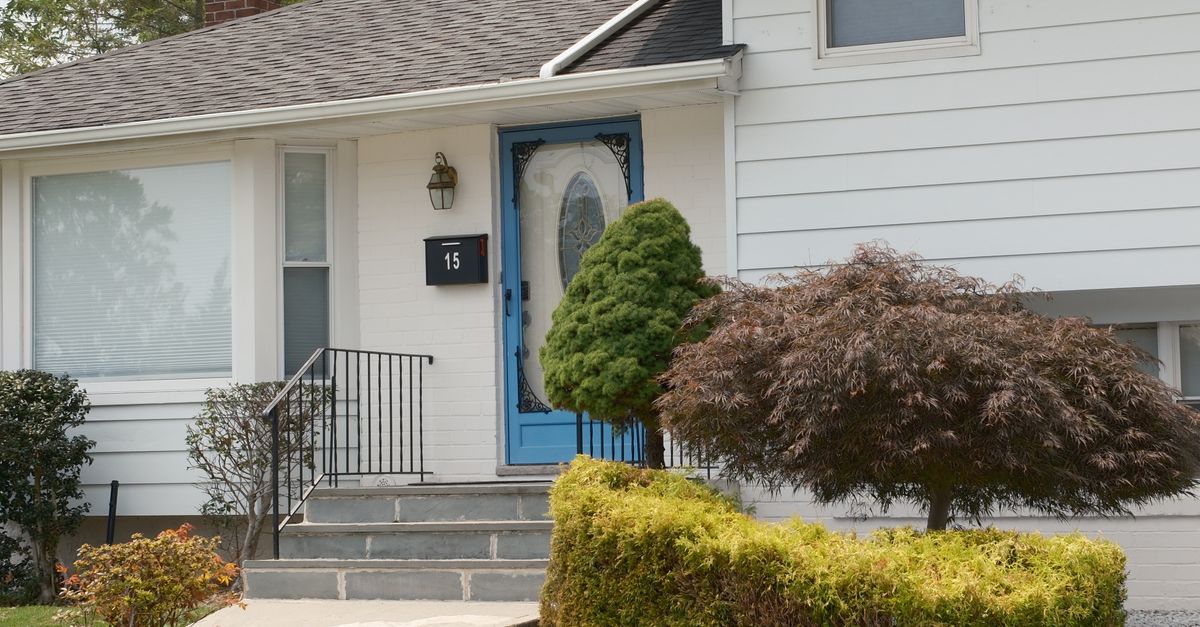 Inviting suburban home with a distinctive blue front door and well-kept shrubs.