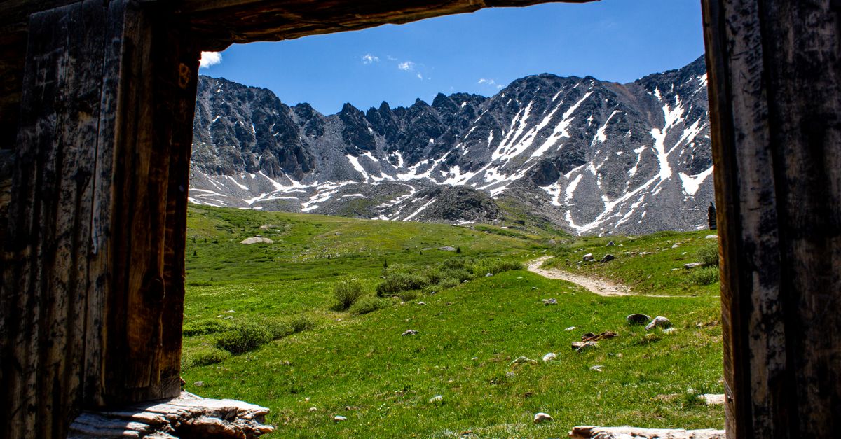 Scenic view of mountains through an old cabin window in Frisco, Colorado with clear skies.
