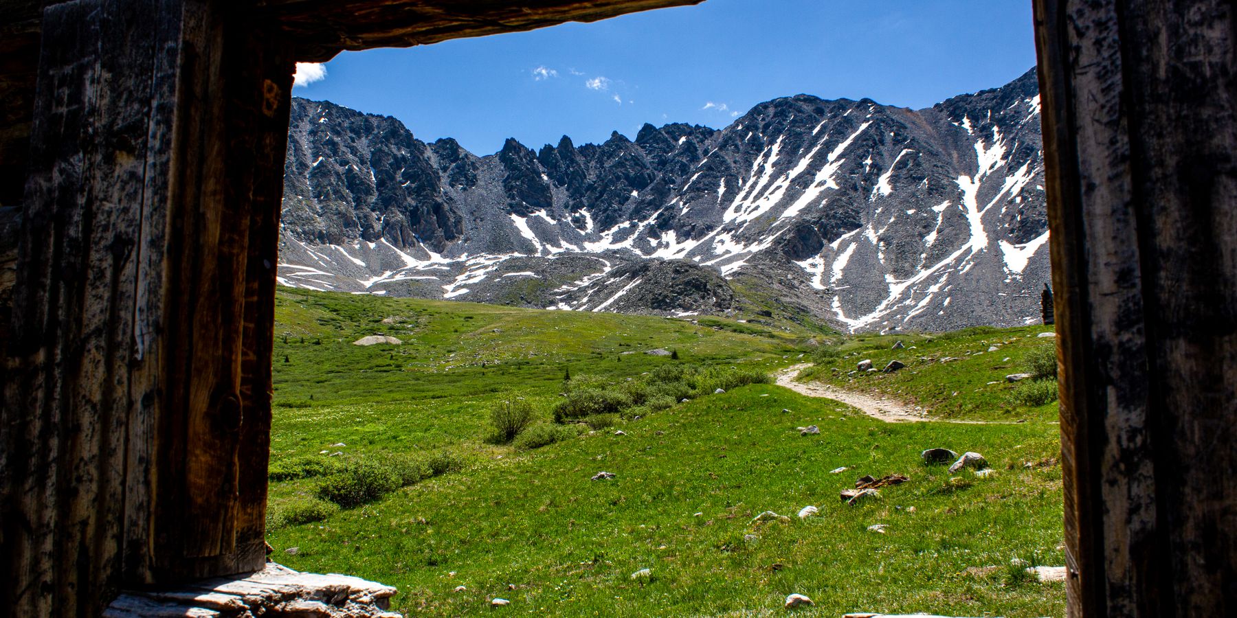 Scenic view of mountains through an old cabin window in Frisco, Colorado with clear skies.