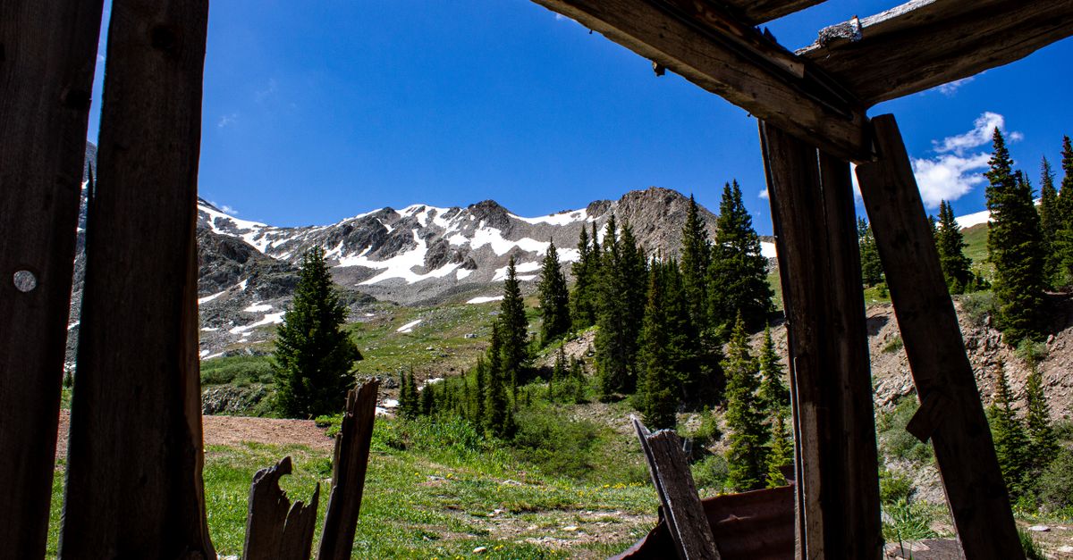View of snow-capped mountains from an abandoned cabin in Frisco, Colorado.