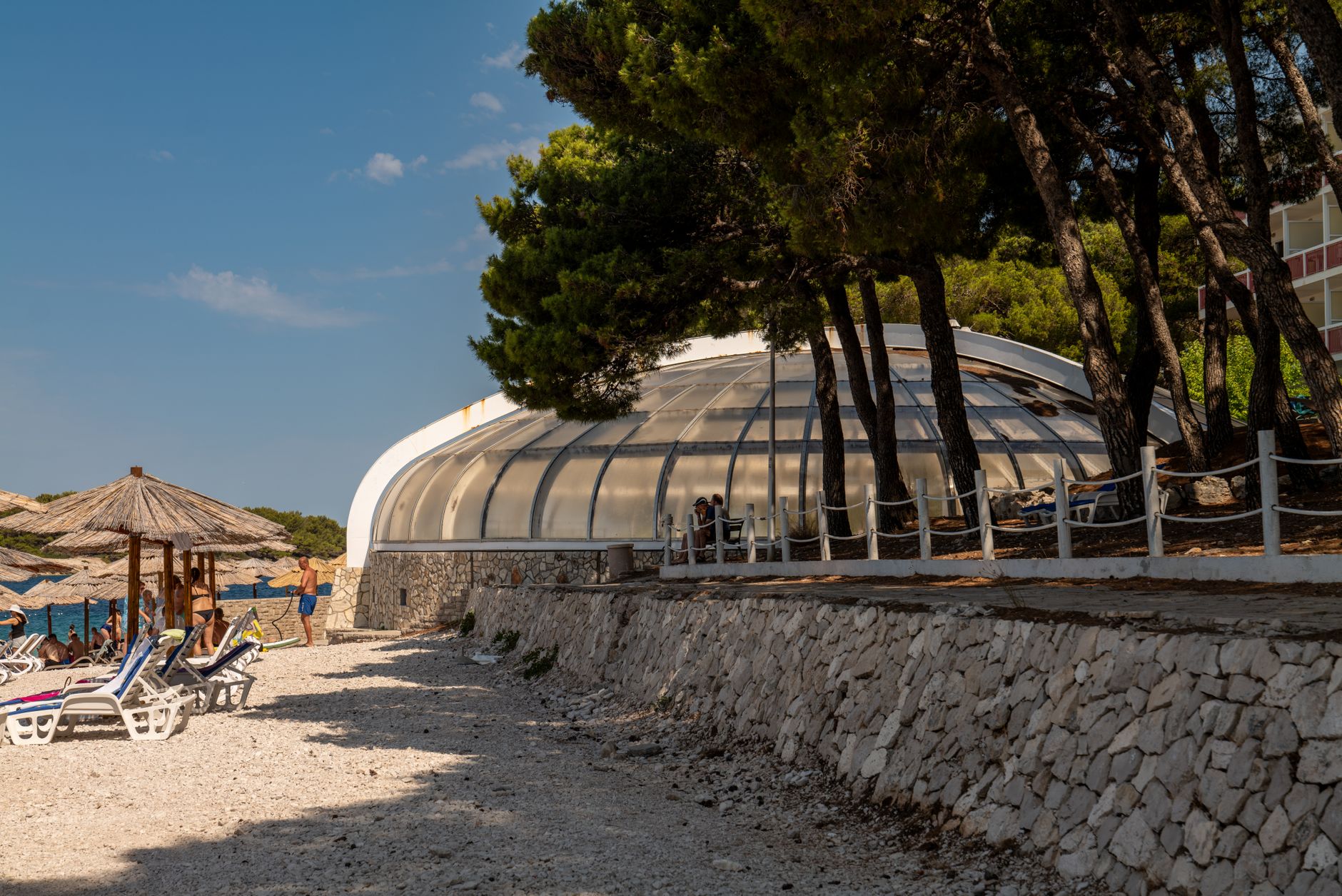 A beach view featuring a dome structure and lounge chairs in Primošten, Croatia.