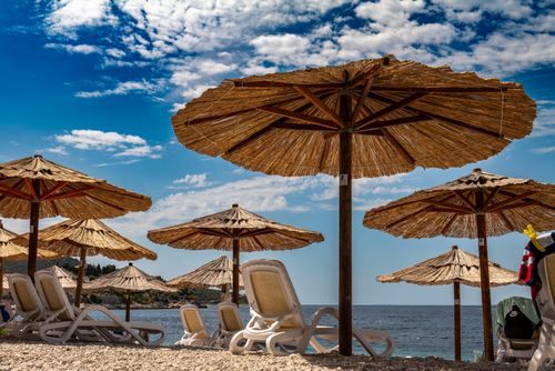 Free Sunny day at Primošten beach with straw umbrellas and lounging chairs. Stock Photo