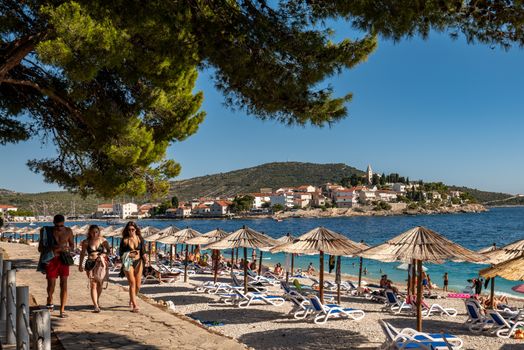 People enjoying a vibrant summer beach in Primošten, Croatia.