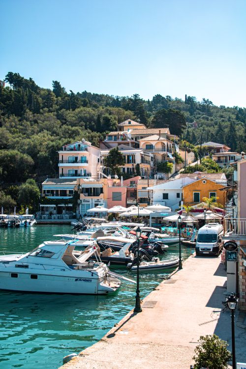 Free A picturesque view of a Greek marina with yachts and colorful hillside houses. Stock Photo