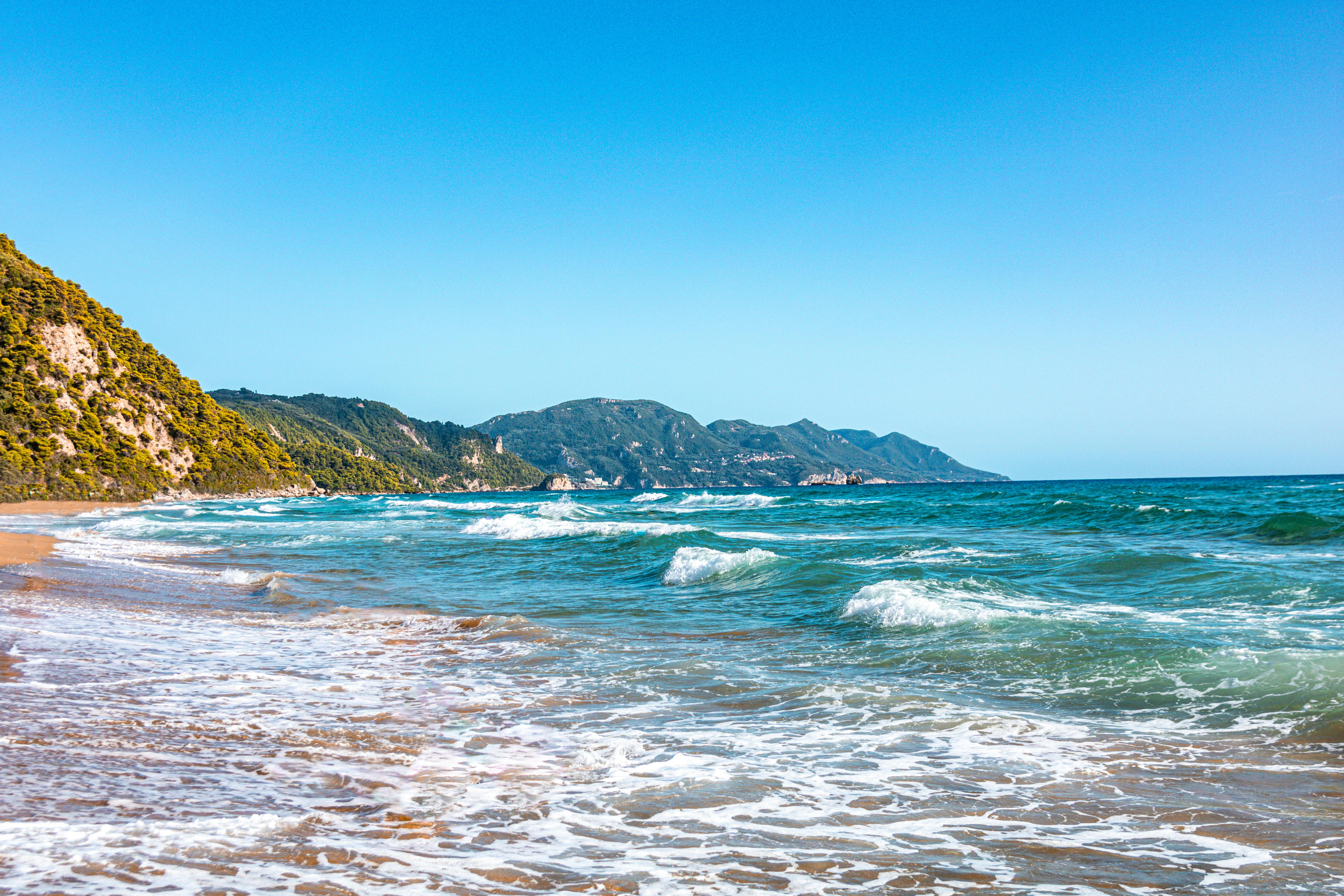 Explore the serene beach in Greece with blue waves and sunny summer vibes. Perfect for travel inspiration.