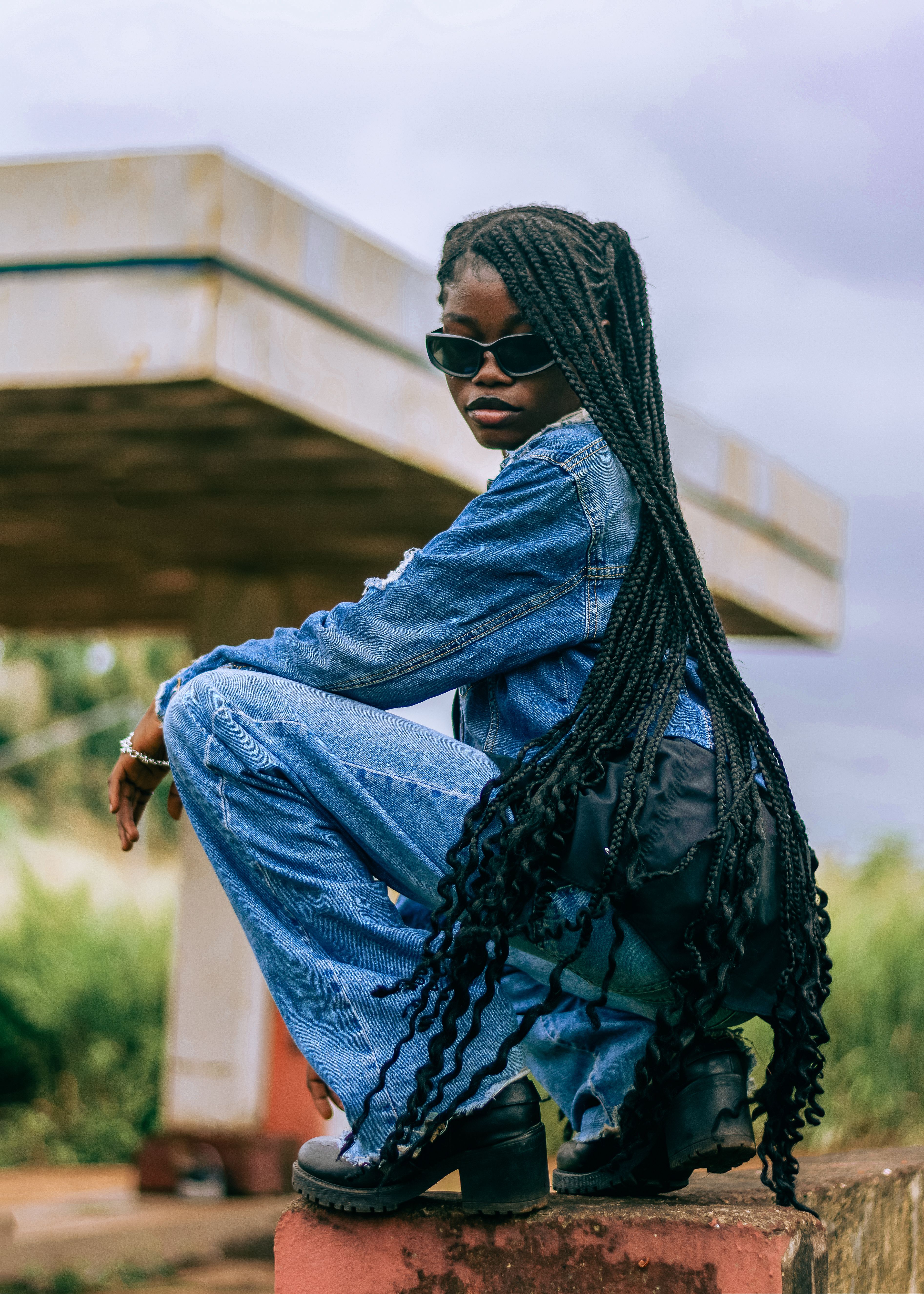 Stylish woman in denim outfit with sunglasses posing confidently outdoors.