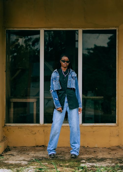 Free Stylish woman stands confidently in casual denim against an urban backdrop, exuding modern fashion. Stock Photo