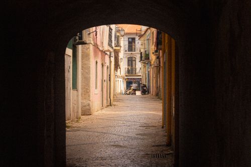 Free Romantic view of a sunlit alleyway in Setúbal, Portugal, with vibrant architectural charm. Stock Photo