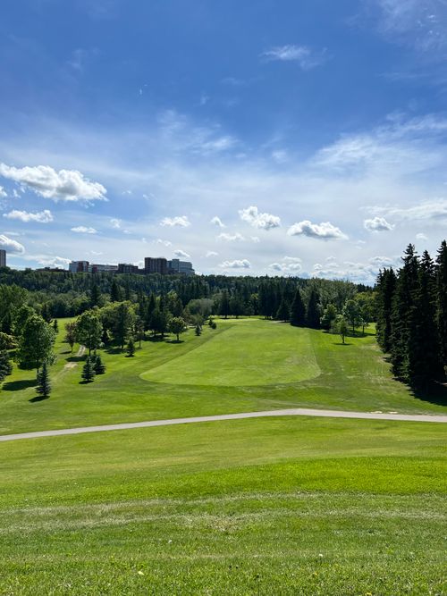 Free Lush green golf course surrounded by trees under a clear blue sky, perfect summer setting. Stock Photo