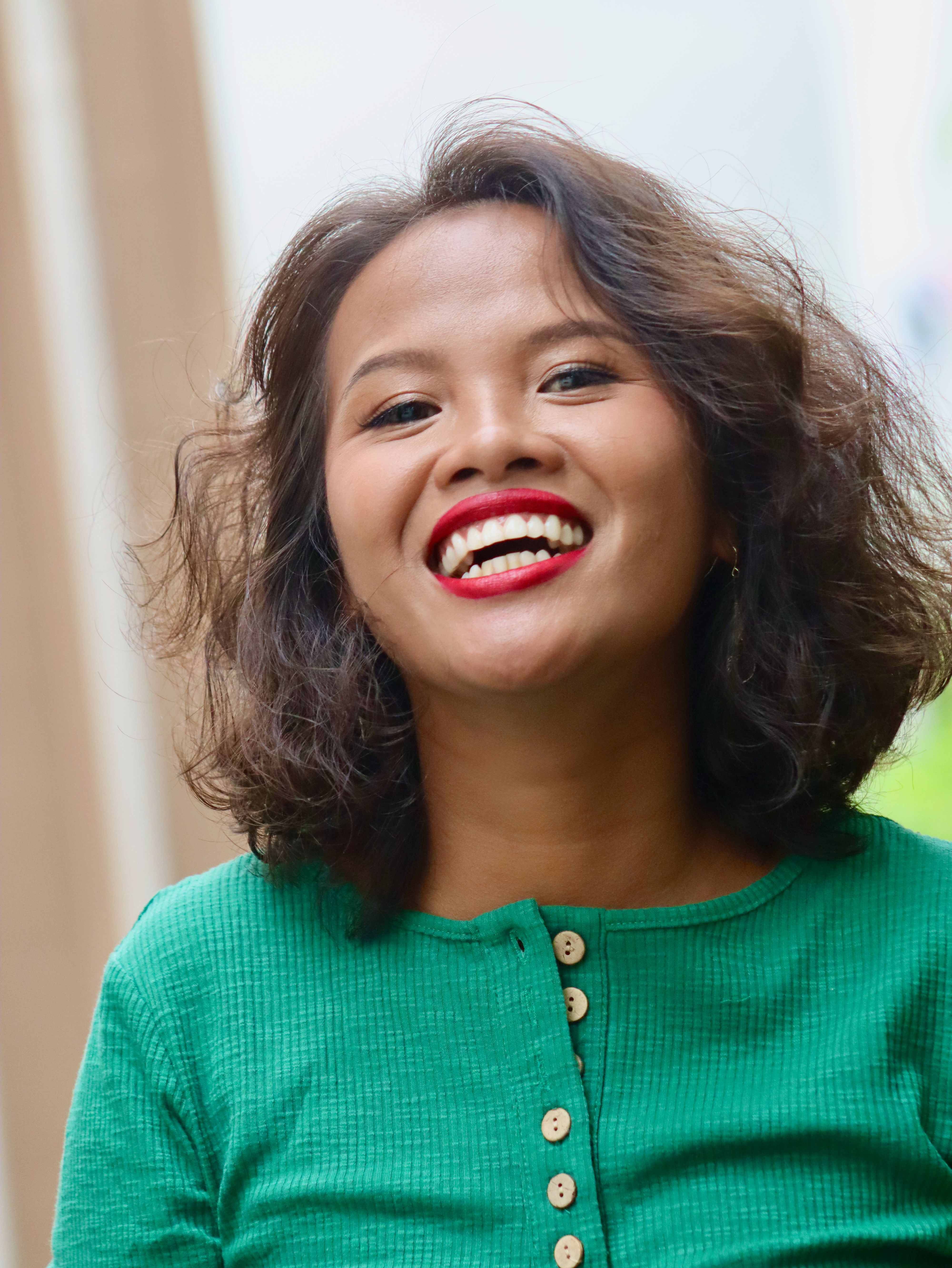 Energetic portrait of a smiling woman in a green top, captured outdoors in Cebu City, Philippines.