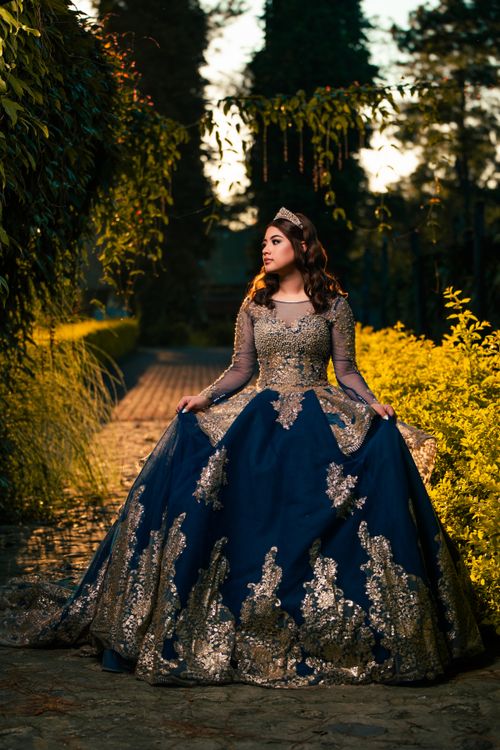 Free A woman in a luxurious royal blue gown stands gracefully in an enchanting garden. Stock Photo