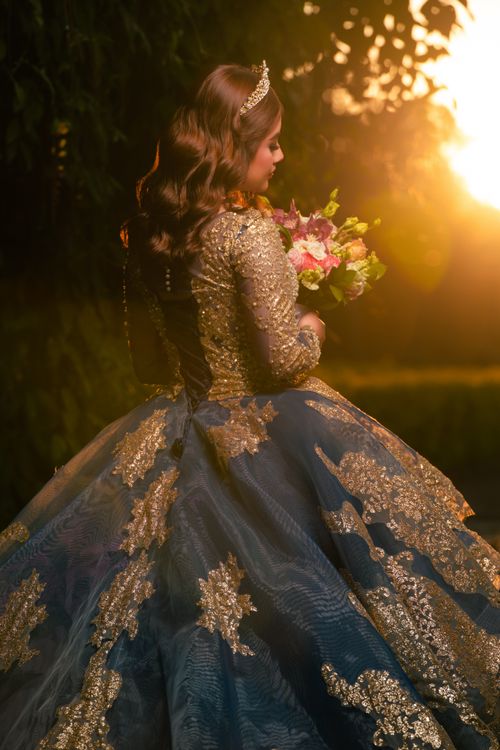 Free Elegant woman in an ornate gown holding a bouquet at sunset, exuding grace and sophistication. Stock Photo