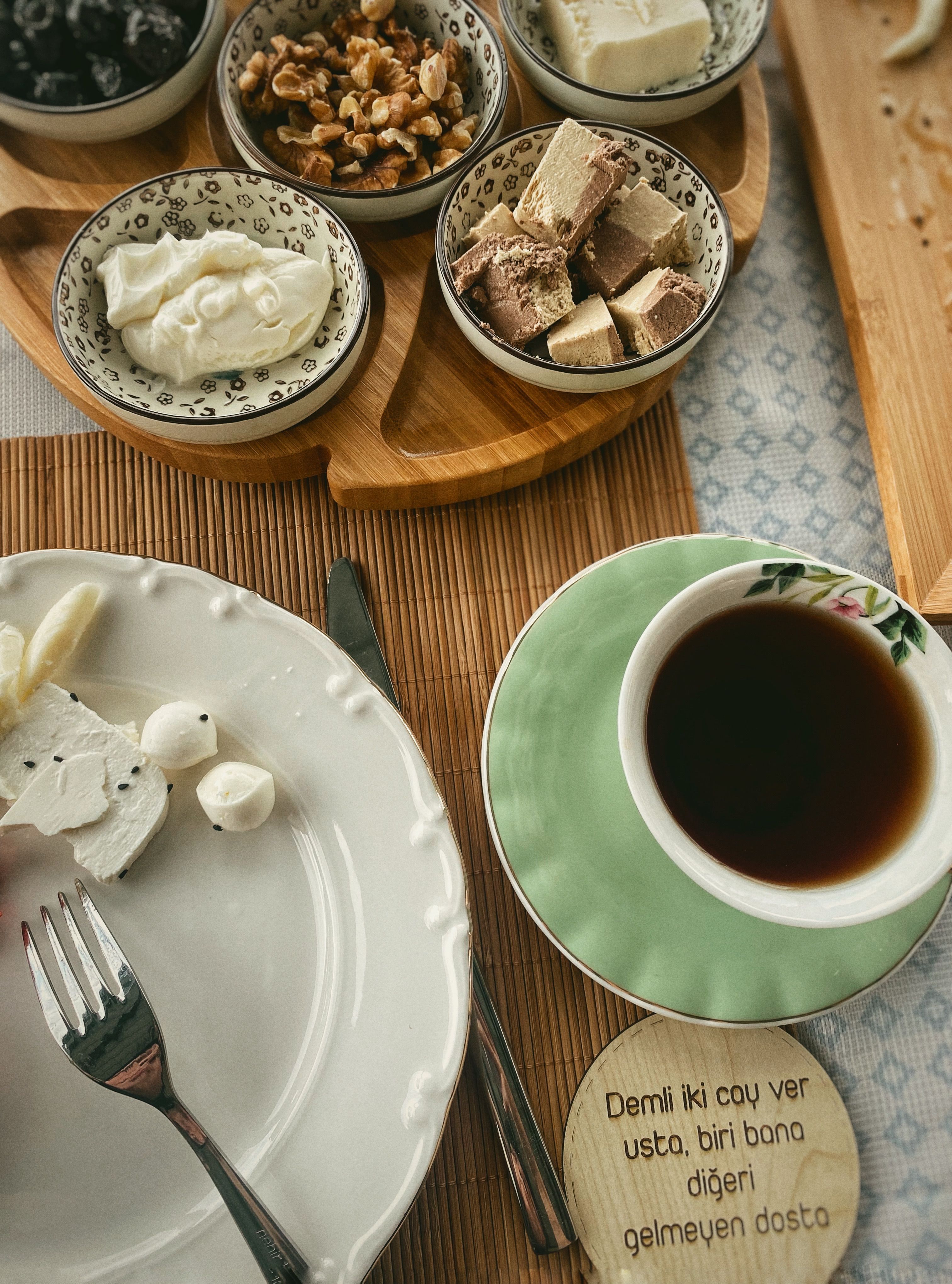 A top view of a traditional Turkish breakfast spread with tea and assorted cheeses on a wooden platter.
