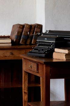 Classic office setting with antique typewriter and stacked old books.