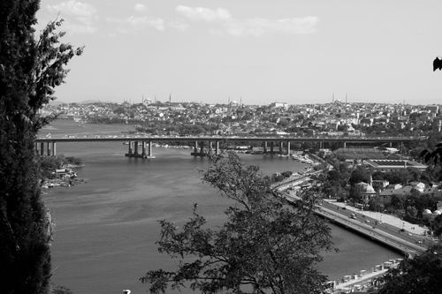 Free Black and white view of a cityscape featuring a river, bridge, and urban landscape. Stock Photo