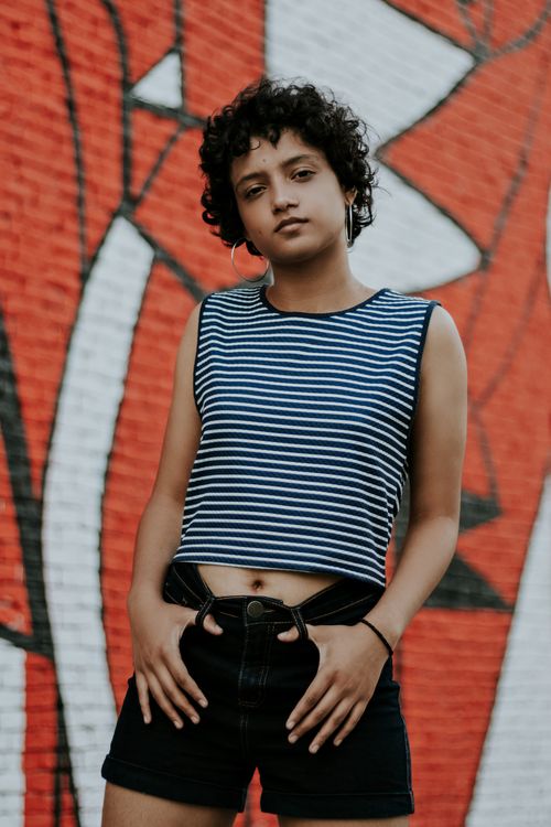 Free Portrait of a fashionable young woman posing in front of graffiti wall outdoors. Stock Photo