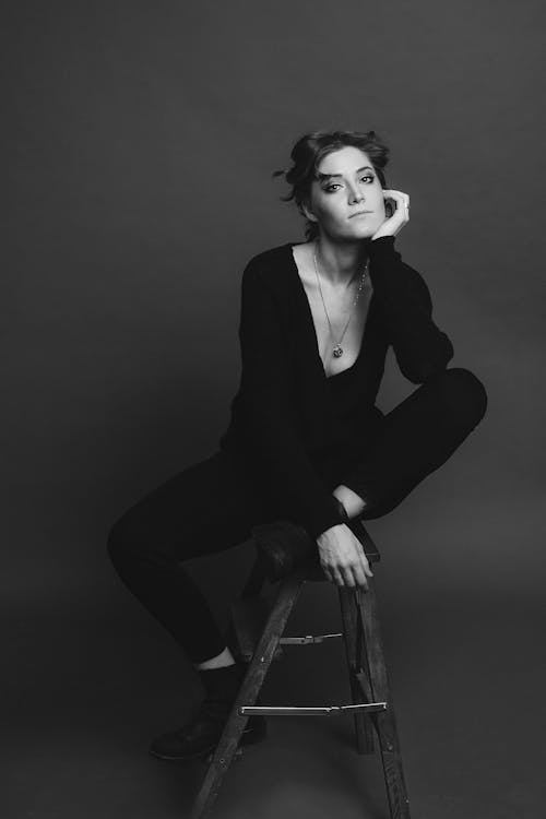 Greyscale Photography of Woman Sitting on Wooden Stool