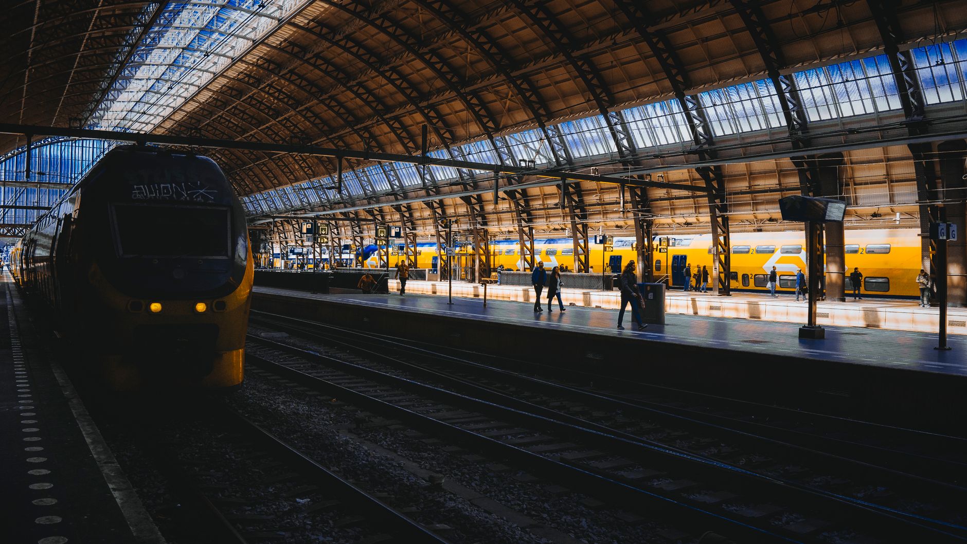 Interrail vs Eurail Pass decision at Amsterdam Centraal with yellow trains and ornate station