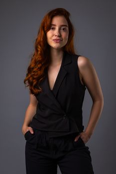 Studio portrait of a confident woman with red hair in stylish black attire.