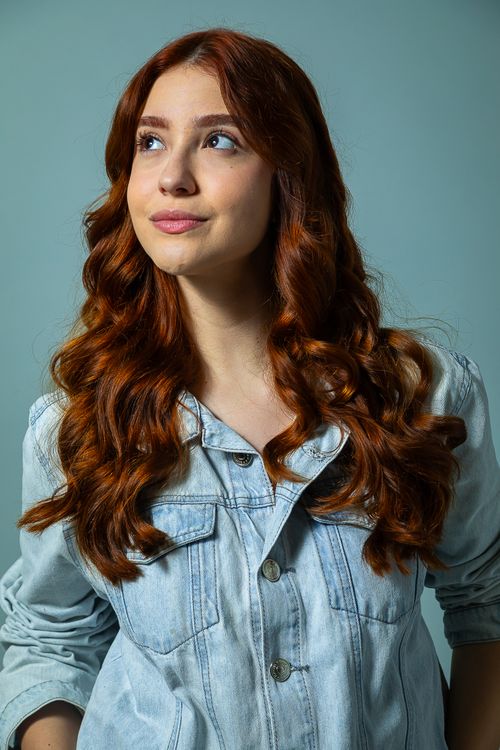 Free Portrait of a young woman with red hair in a denim jacket looking upwards. Stock Photo
