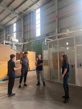 Group of adults discussing in a spacious industrial warehouse setting.