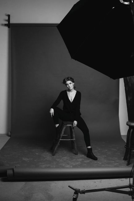 Elegant black and white studio portrait of a model posing against a solid backdrop.
