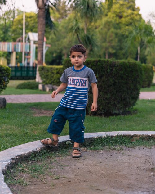 Free A portrait of a young boy playing in a lush park, showcasing innocence and joy. Stock Photo
