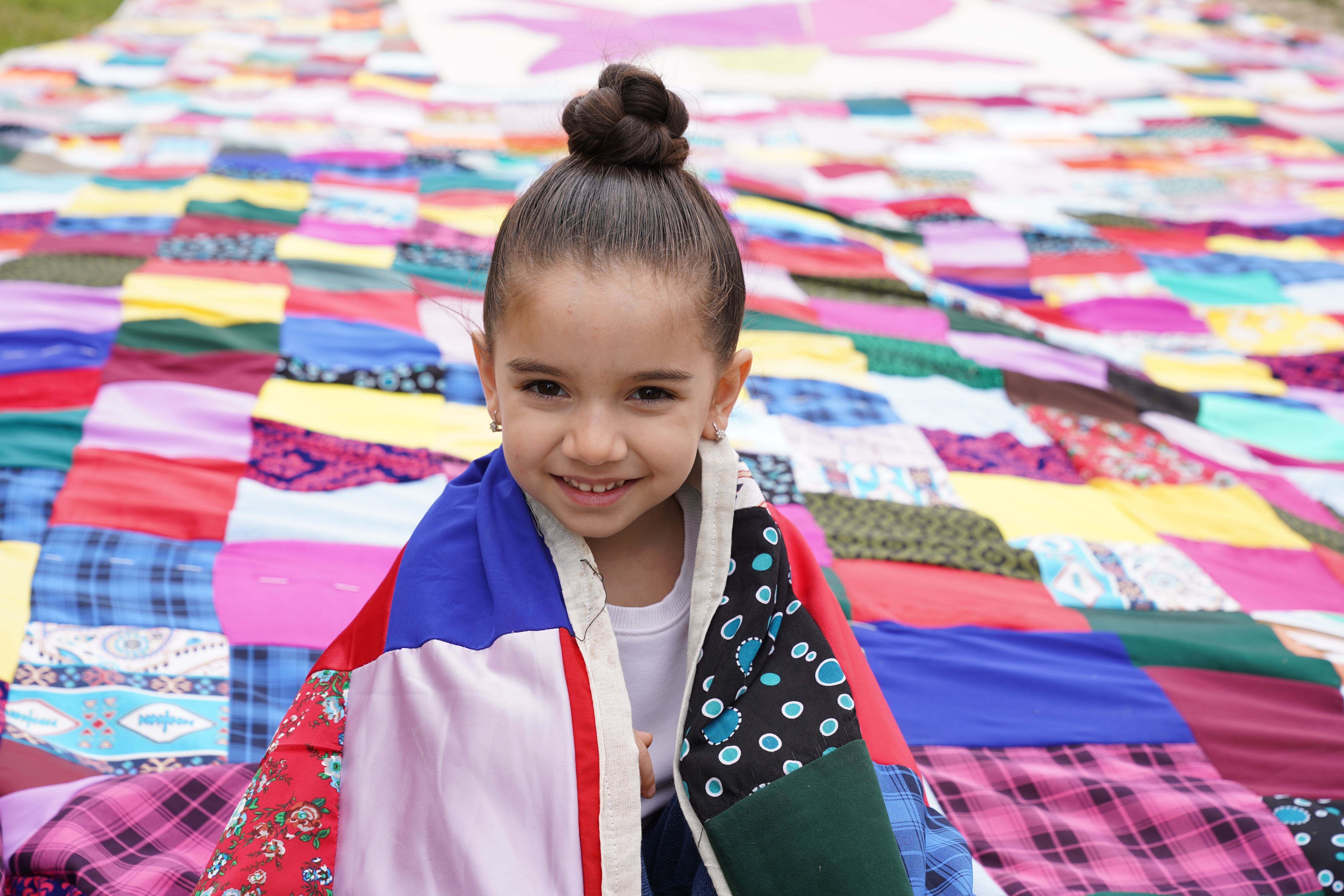 Joyful Child Wrapped in Colorful Patchwork Quilt · Free Stock Photo