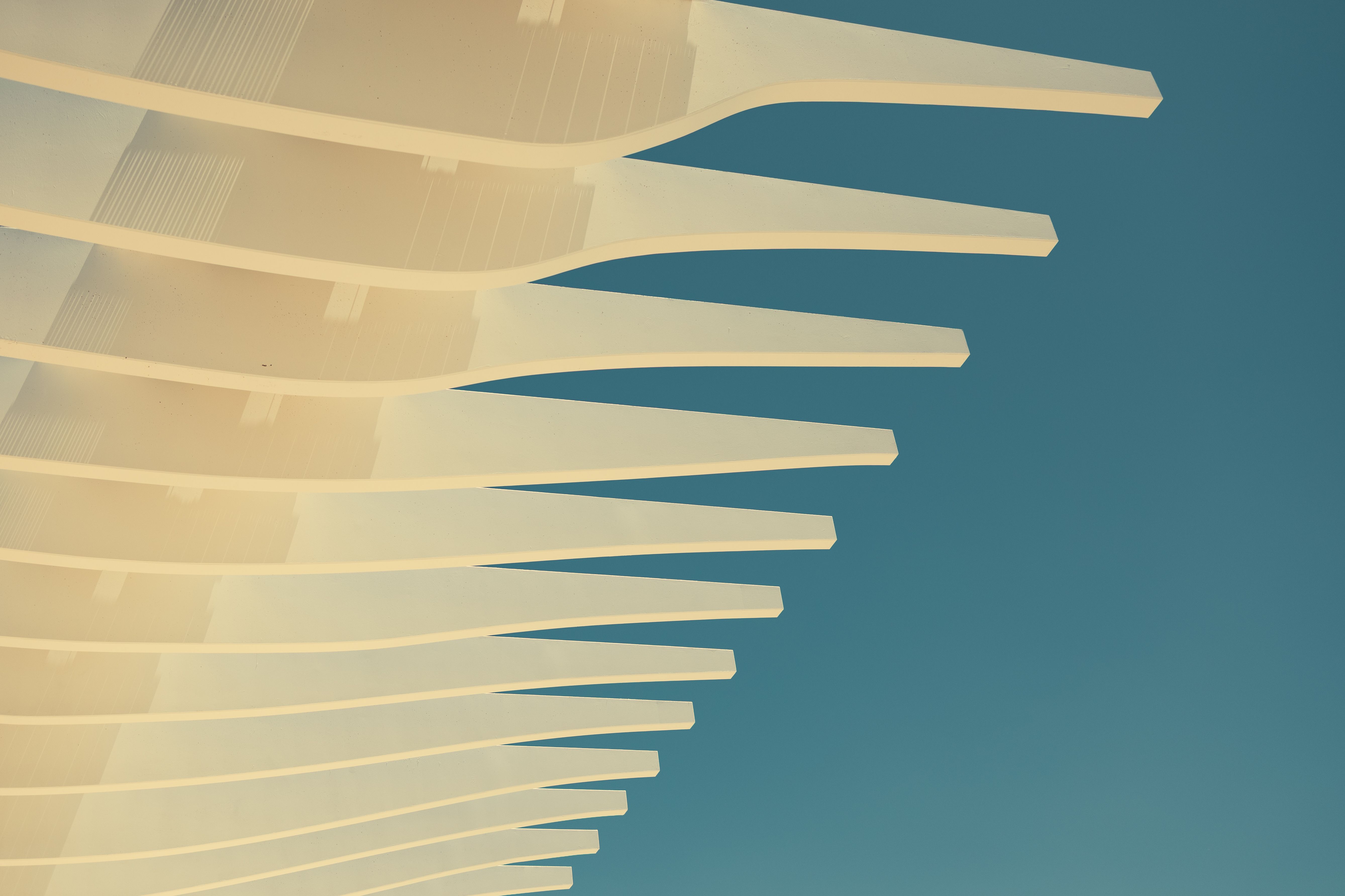 Abstract view of a modern architectural overhang against a clear blue sky, showcasing creativity.