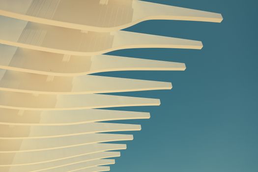Abstract view of a modern architectural overhang against a clear blue sky, showcasing creativity.