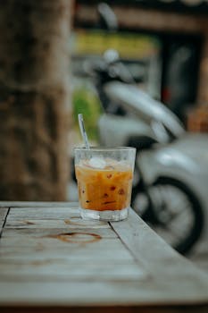 Iced coffee on a rustic table with a motorcycle in the background, creating a laid-back vibe.