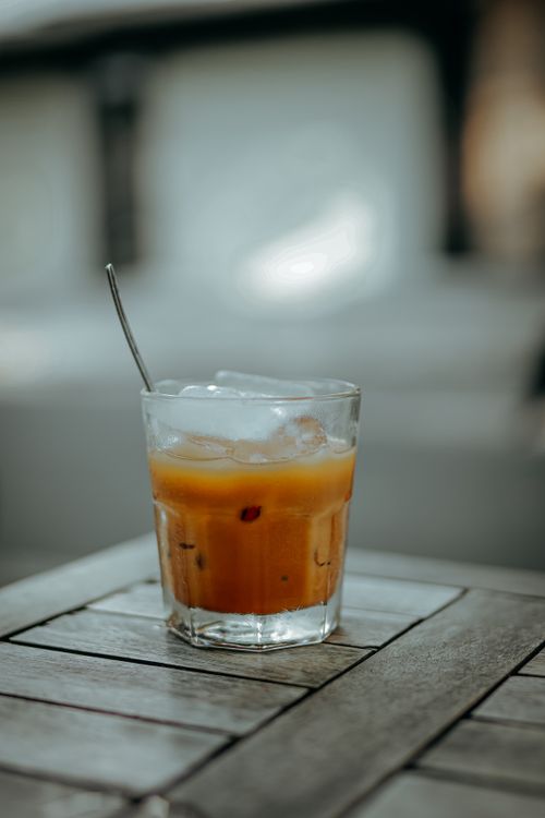 Free A close-up of a refreshing iced orange drink in a glass on a wooden table. Stock Photo