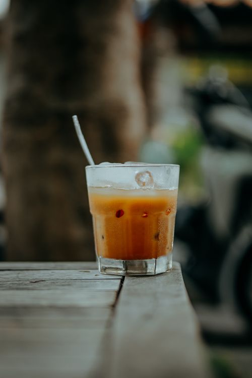 Free Chilled iced coffee in a glass with straw on a rustic wooden table outdoors, perfect for summer. Stock Photo