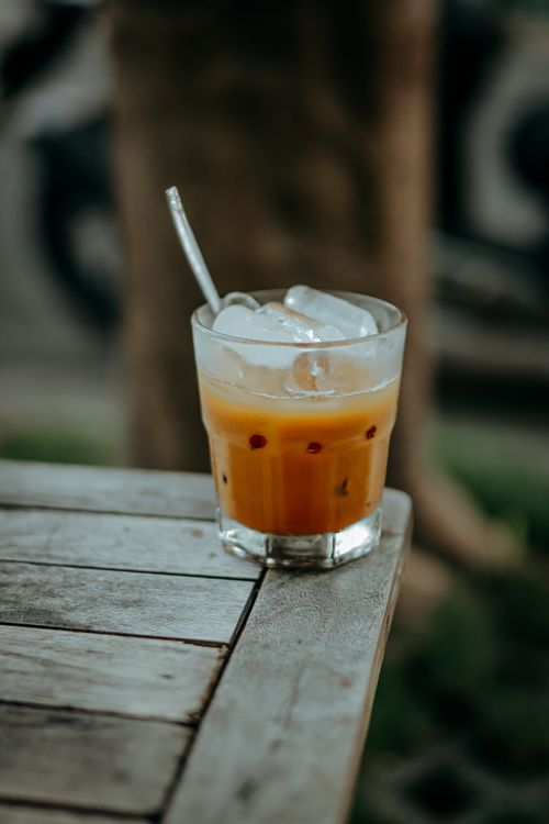 Free Refreshing iced orange beverage in a glass on a rustic outdoor table. Stock Photo