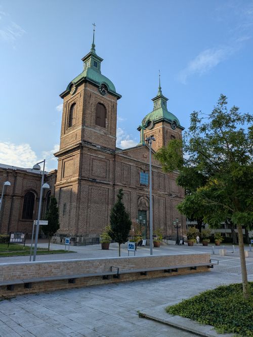 Free A stunning historic brick cathedral with twin towers and green roofs under a clear blue sky. Stock Photo