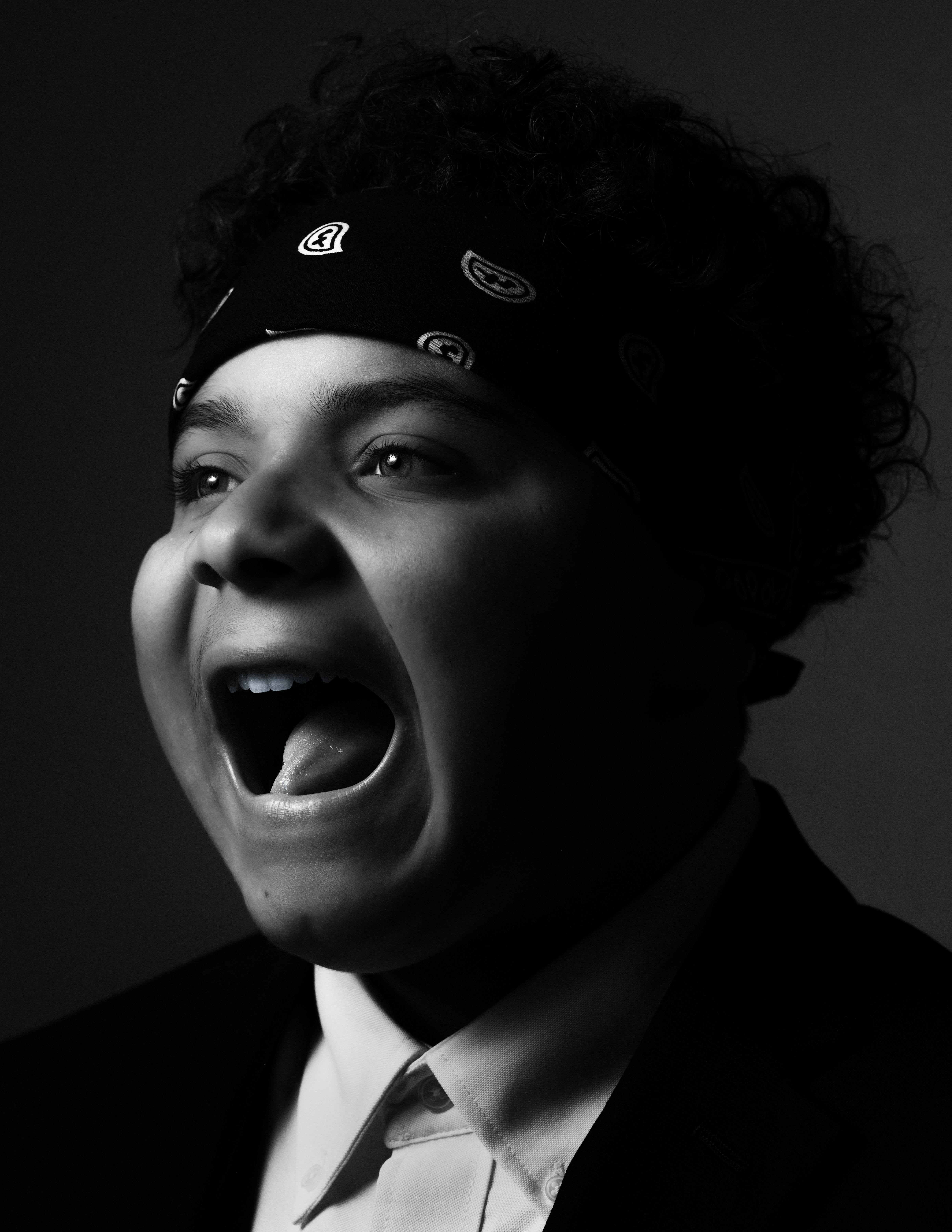 Dramatic black and white portrait of a young adult in expressive mood, wearing a bandana.