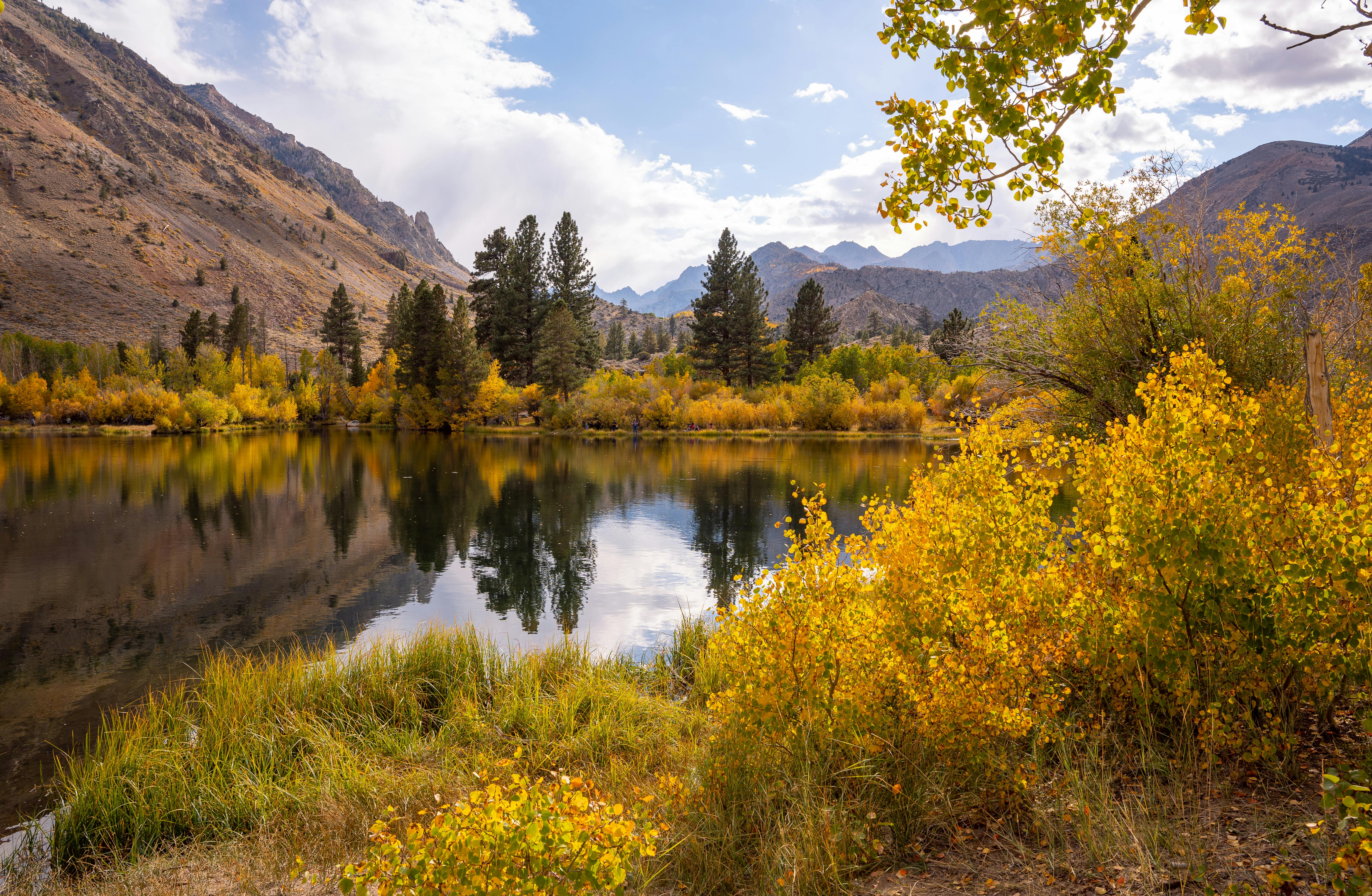 Serene autumn landscape of a mountain lake with vibrant fall foliage in Bishop, California.